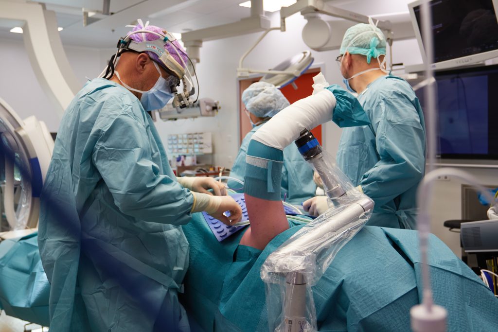 Artsen voeren een thoracic outlet decompressie uit met hulp van geavanceerde apparatuur, waaronder een robotarm.