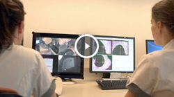 Twee personen in witte uniformen bekijken radiotherapiescans op een computer in het Catharina Ziekenhuis.