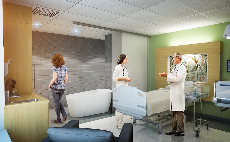 Ziekenhuiskamer met bed, twee pratende zorgmedewerkers, een persoon loopt naar het bad. Moderne inrichting en medische apparatuur.