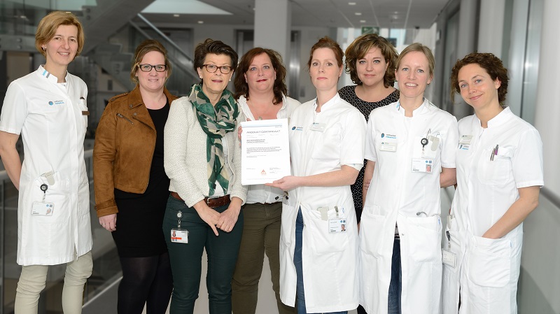 Acht vrouwen, deels in witte uniformen en deels in zakelijke kleding, poseren in het Catharina Ziekenhuis, twee met een certificaat.