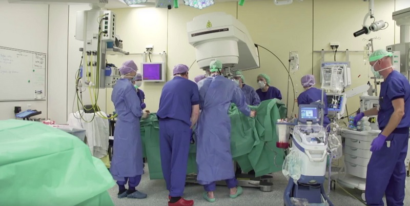 Artsen in OK-kleding en maskers voeren een operatie uit om kanker te diagnosticeren, omringd door medische apparatuur.