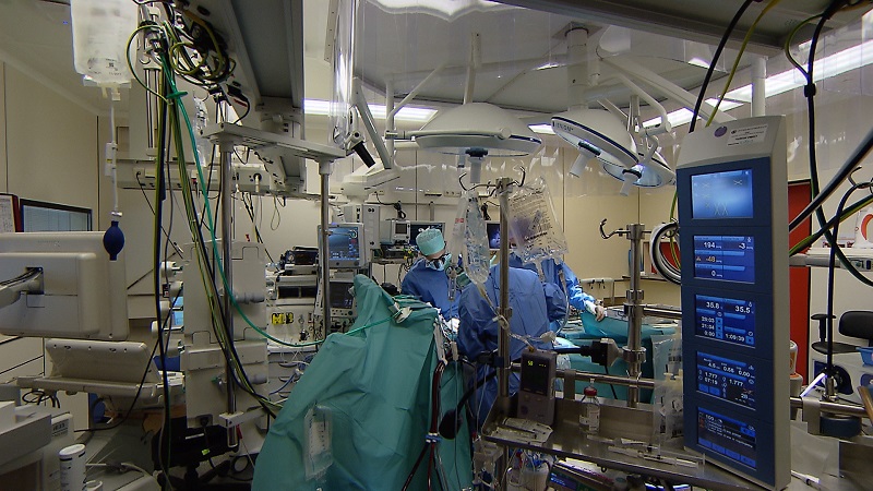 Ricardo Verkooijen leidt een team artsen in OK-kledij tijdens een openhartoperatie in een operatiekamer vol medische apparatuur.