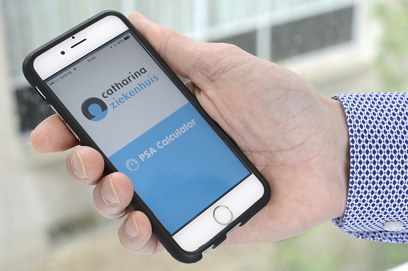 Persoon houdt iPhone met de Catharina Ziekenhuis PSA Calculator-app. App toont logo en helpt PSA-waarde voor prostaatkanker te bepalen.