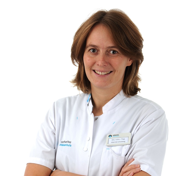 Vrouw met halflang bruin haar in witte artsenjas en naambordje, armen over elkaar, glimlacht. Internist-oncoloog Catharina Ziekenhuis.
