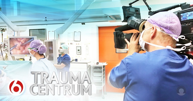 Cameraman filmt operatieteam in helder verlichte OK van Catharina Ziekenhuis. Trauma Centrum' en rood 6-logo op voorgrond.