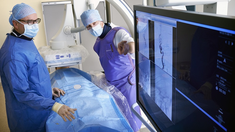 Twee medisch specialisten in scrubs en maskers bekijken scans bij hun 200ste trombectomie in het Catharina Ziekenhuis.