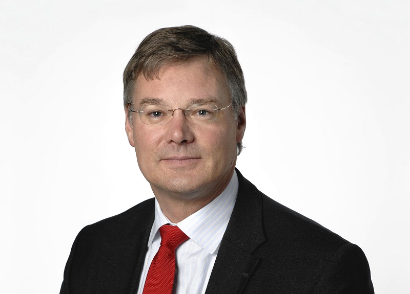 Man met kort lichtbruin haar, bril, neutrale blik, donker pak, wit overhemd, rode stropdas; witte achtergrond. Raad van Toezicht Catharina Ziekenhuis.