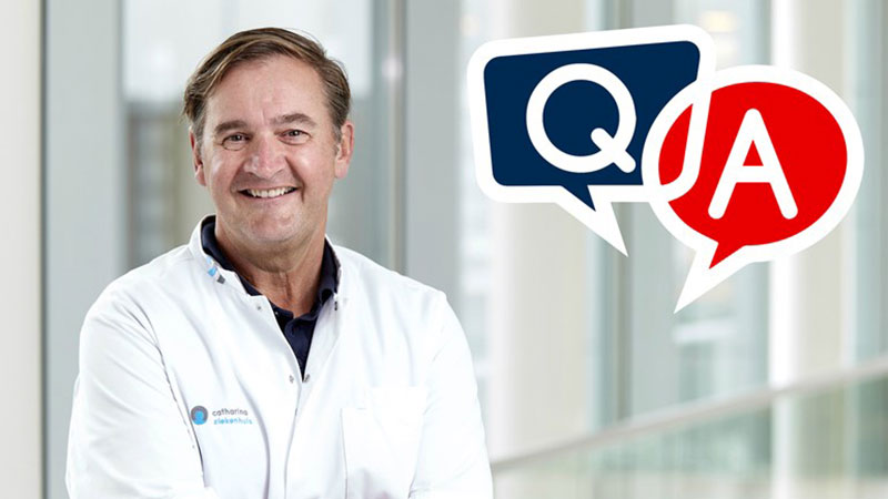 Man in witte labjas glimlacht binnen. Achter hem staan blauwe en rode Q&A-spraakballonnen over prostaatkanker.