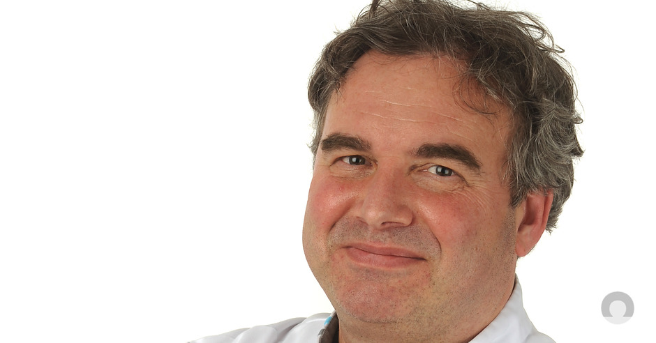 Chirurg dr. Jean Paul de Zoete, grijs haar, lichte glimlach, wit overhemd, witte achtergrond, winnaar samen beslissen-award.