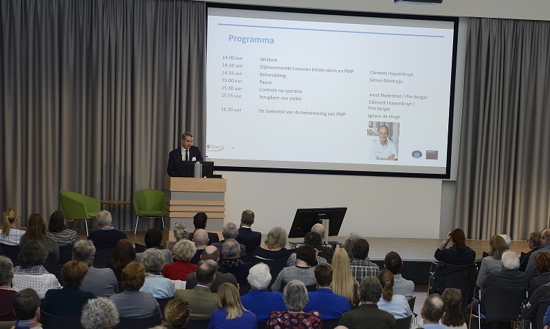 Spreker bij katheder in het Catharina Ziekenhuis; achter hem een scherm met het programma, tijden en sprekers.