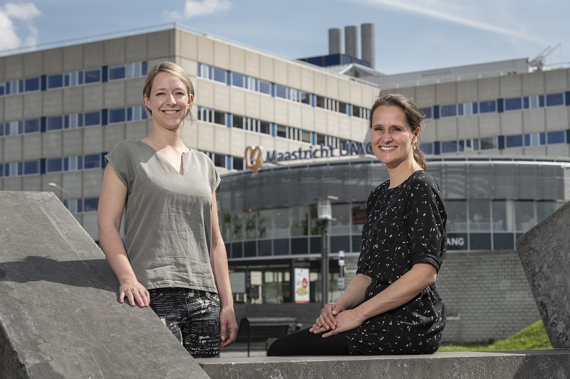 Twee vrouwen poseren lachend voor "Maastricht UMC+" op een zonnige dag, verwijzend naar risico op zonneschade.