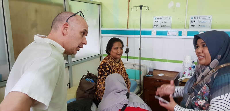 Gynaecoloog-oncoloog Ralph Hermans luistert naar een vrouw met hoofddoek, terwijl een andere vrouw op een ziekenhuisbed zit in Indonesië.