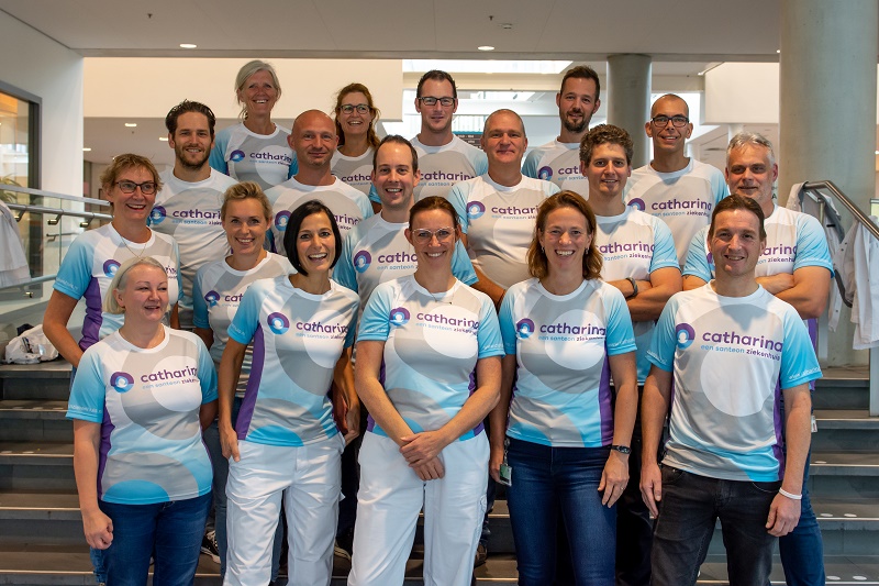 Groep van 18 mannen en vrouwen op een val, in Catharina Ziekenhuis-shirts, klaar voor de Marathon Eindhoven.