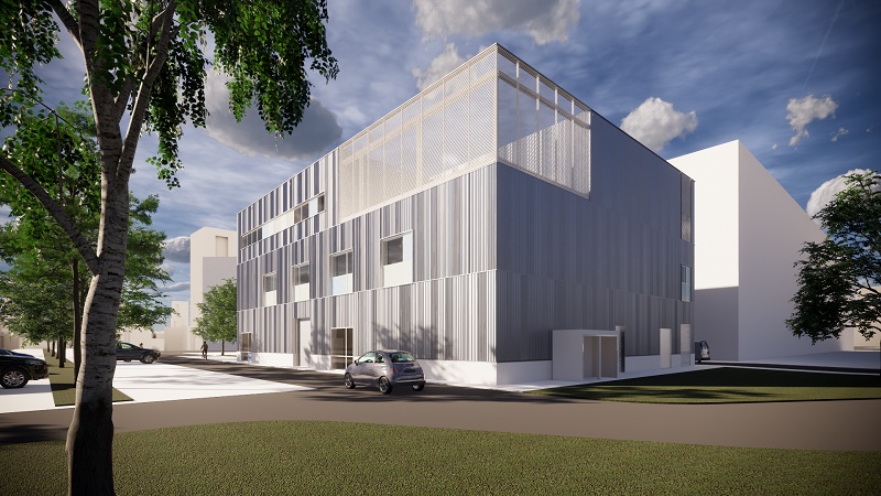 Modern, rechthoekig gebouw met metalen gevel en grote ramen, drie verdiepingen, omringd door bomen, auto's en gras.