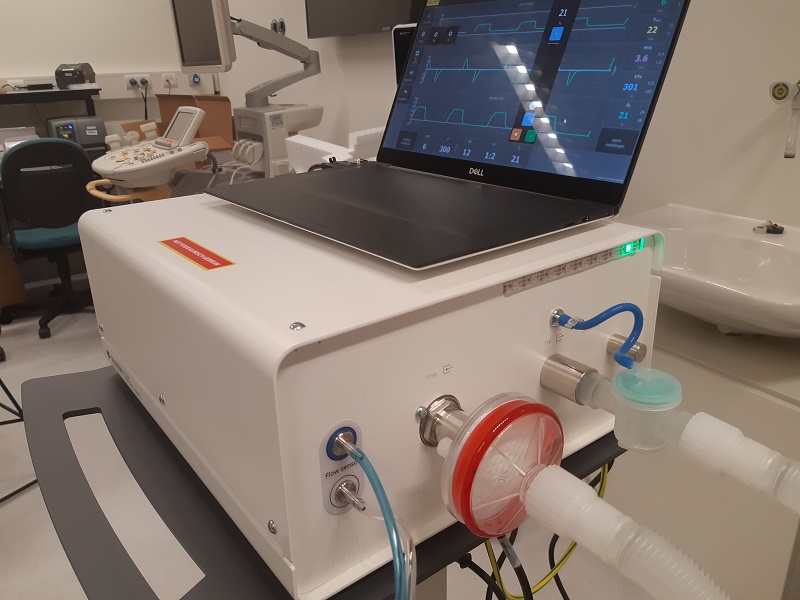 Beademingssysteem met slangen op een kar, laptop toont vitale functies. In klinische setting in Catharina Ziekenhuis.
