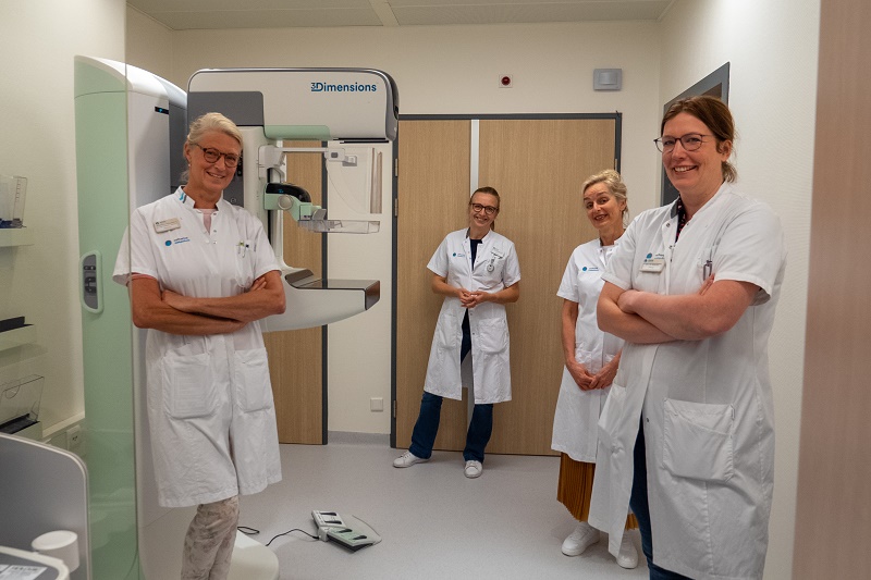 Vier medisch specialisten in het Catharina Ziekenhuis staan naast een 3D-mammografieapparaat, klaar voor borstonderzoek.