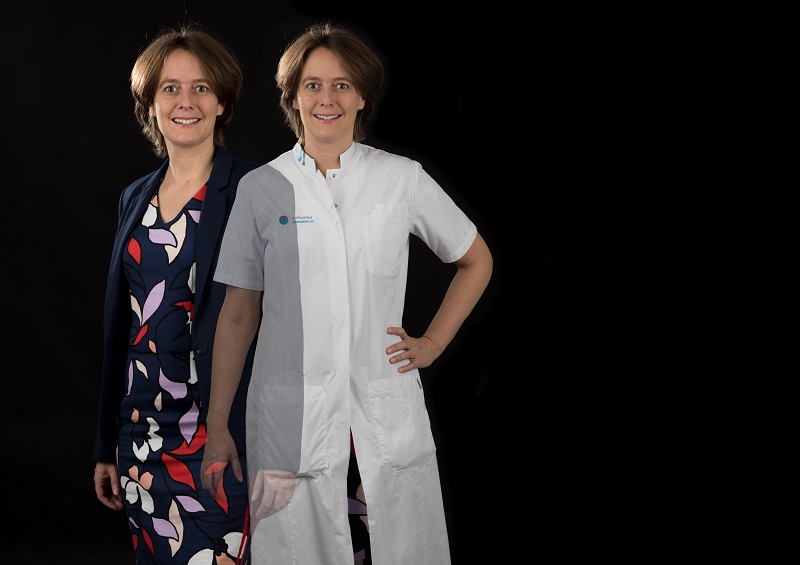 Twee vrouwen met vergelijkbaar kapsel staan naast elkaar; een in bont jurkje met blazer, de ander in witte doktersjas over zelfde jurkje.