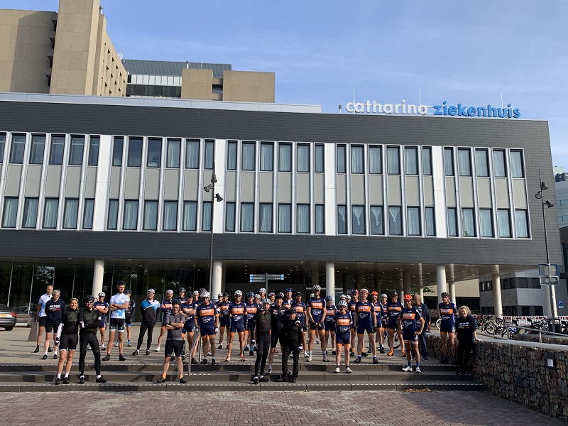 Een groep wielrenners in hetzelfde tenue staat voor het Catharina Ziekenhuis, verzameld voor een goed doel.