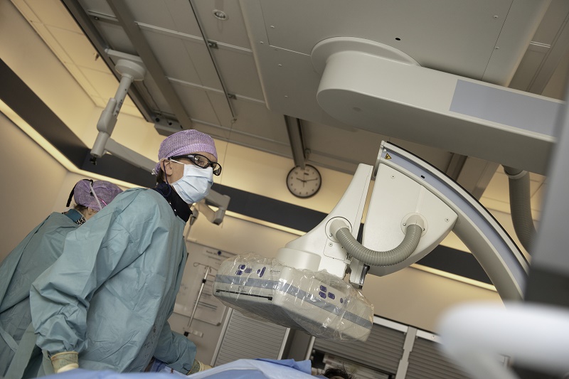 Medisch personeel bedient apparatuur bij Catharina Ziekenhuis met nieuwe techniek; klok zichtbaar op de achtergrond.
