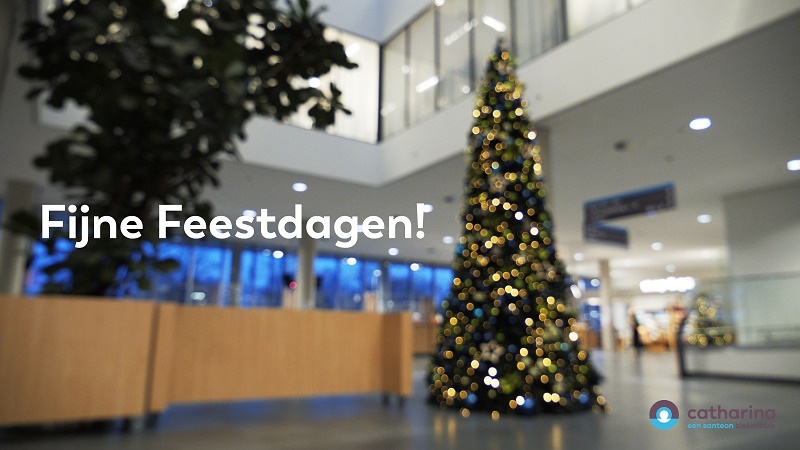 Versierde kerstboom met lampjes in moderne lobby. Tekst "Fijne Feestdagen 2020" en Catharina ziekenhuislogo rechtsonder.