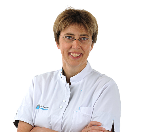 Persoon met kort bruin haar en bril, draagt een witte doktersjas en glimlacht, staat met gekruiste armen voor een witte achtergrond.
