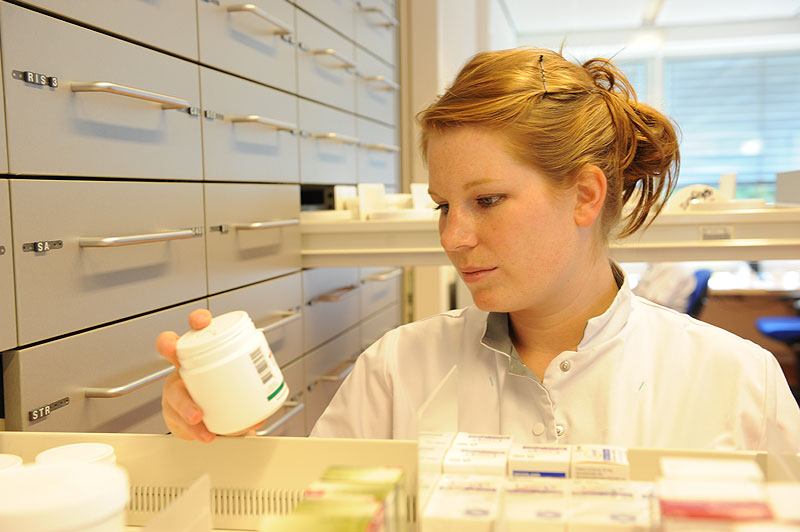 Een apotheker in witte jas bekijkt een medicijnflesje voor medicijnkasten in Catharina Ziekenhuis, Top Employer 2015.