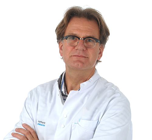 Een man van middelbare leeftijd met bril en kort bruin haar draagt een witte labjas en staat met gekruiste armen voor een witte achtergrond.