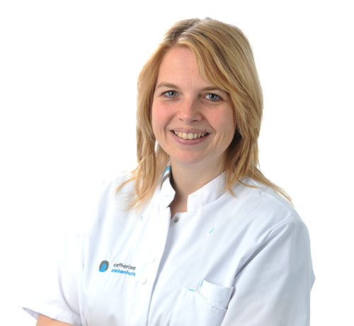 Vrouw met halflang blond haar draagt een witte doktersjas en glimlacht naar de camera voor een witte achtergrond.
