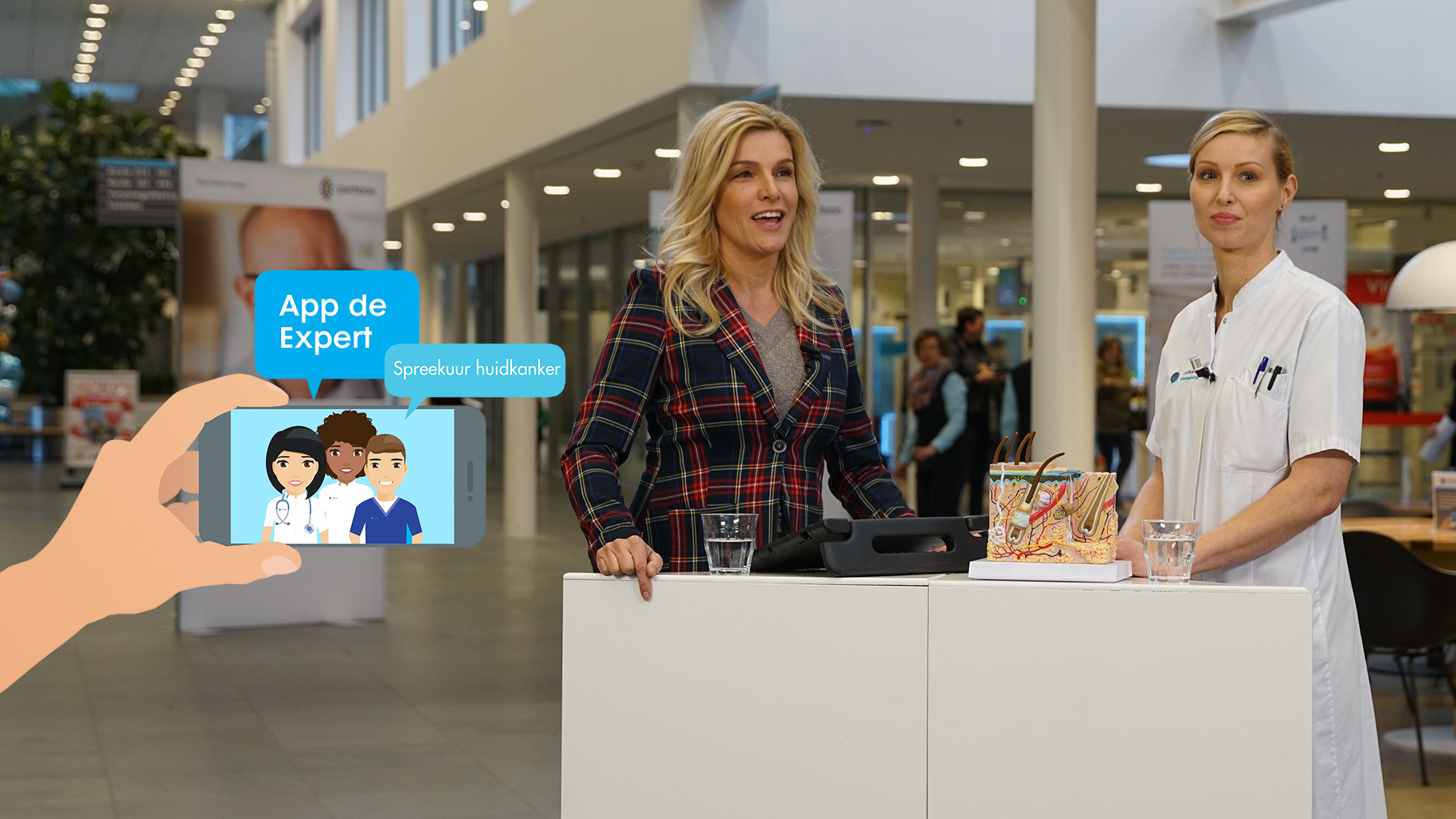 Twee vrouwen staan achter witte tafels; één draagt een geruit colbert, de ander een wit uniform. Voorgrond: telefoon met huidkanker-app.