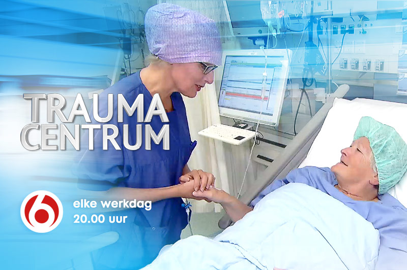 Verpleegkundige met operatiekleding houdt hand van patiënt in ziekenhuisbed. Monitoren zichtbaar. Logo en tekst van Trauma Centrum.