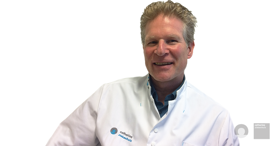 Man met licht haar in een witte doktersjas en blauw shirt lacht naar de camera. Witte achtergrond.
