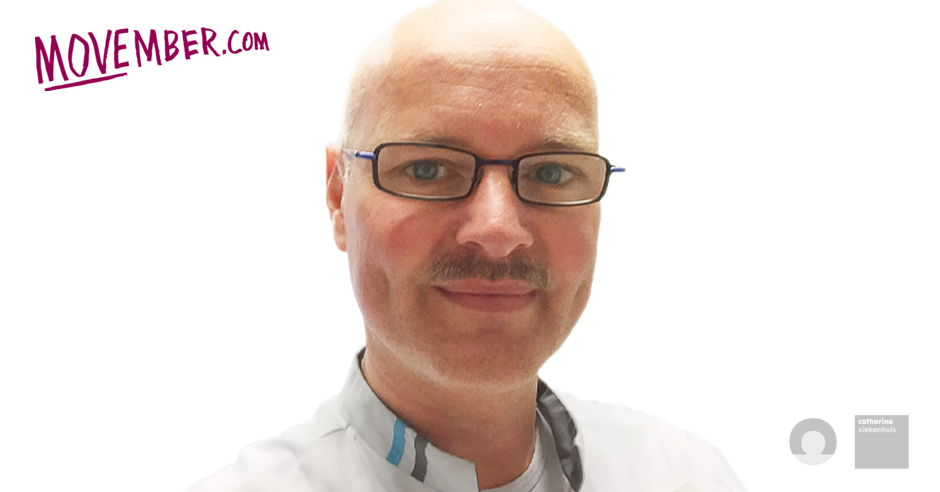 Man met bril, kaal hoofd, witte blouse en snor. In beeld staat paars "Movember.com", over prostaatkanker.
