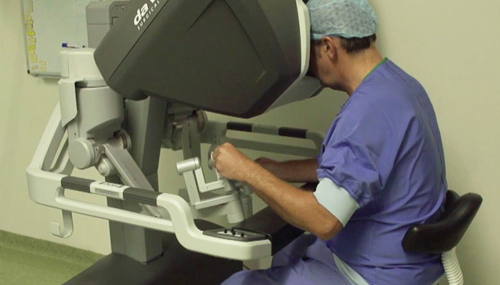 Een persoon in operatiekleding bedient een operatierobot tijdens een prostaatkankerbehandeling in een moderne kliniek.
