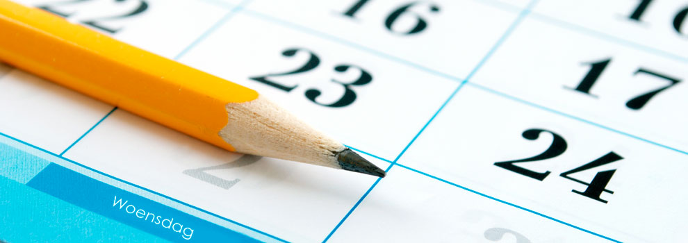 Een geslepen gele potlood ligt op een kalender met grote zwarte cijfers en een blauwe sectie met "Woensdag".