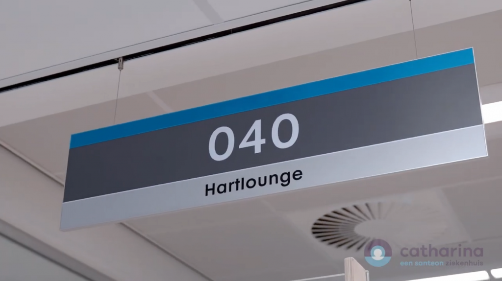 Rechthoekig bord aan plafond met 040 en Hartlounge. Op achtergrond deels plafondrooster en logo Catharina ziekenhuis zichtbaar.