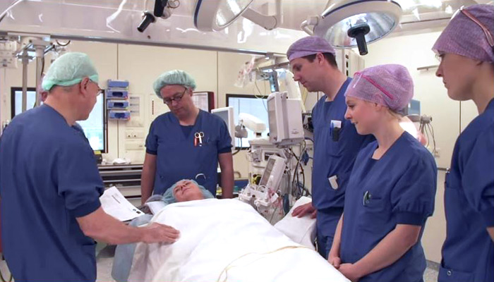 Artsen anesthesiologie en pijngeneeskunde overleggen bij een patiënt op de operatiekamer.