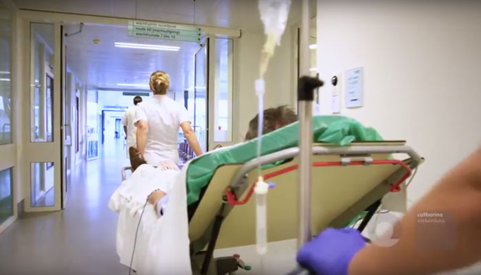 Een patiënt op een brancard wordt in de gang van het Catharina Hart- en Vaatcentrum begeleid door medisch personeel.