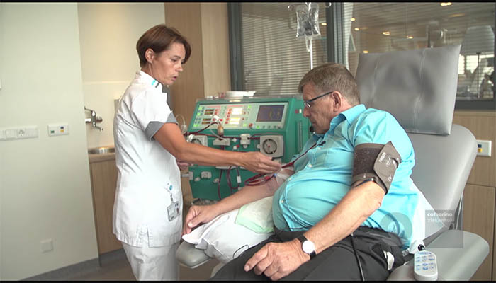 Een verpleegkundige stelt een dialyseapparaat af naast een man met infuus in de arm bij Dialysecentrum Deurne, Catharina Ziekenhuis.
