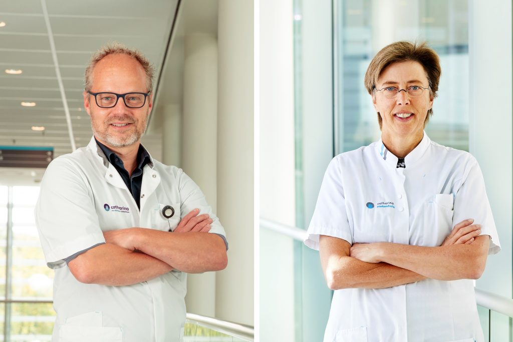 Twee medisch specialisten met gekruiste armen in aparte, lichte gangen van het Catharina Ziekenhuis, dragen witte jassen en brillen.