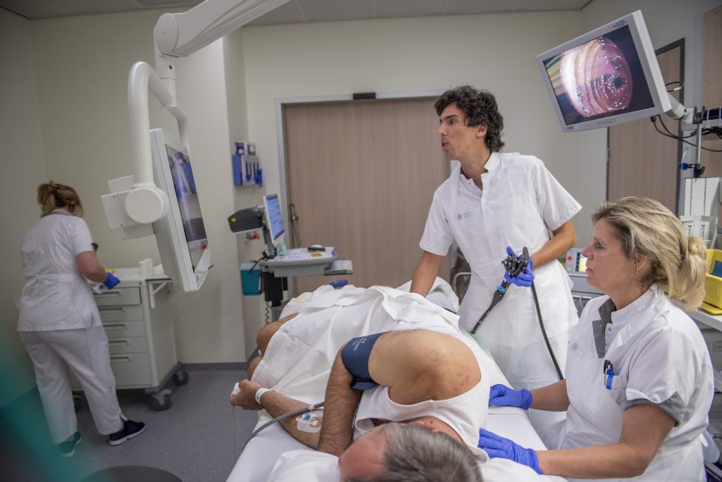Artsen voeren een coloscopie uit in het Catharina Ziekenhuis, met beeld van de procedure op een monitor.