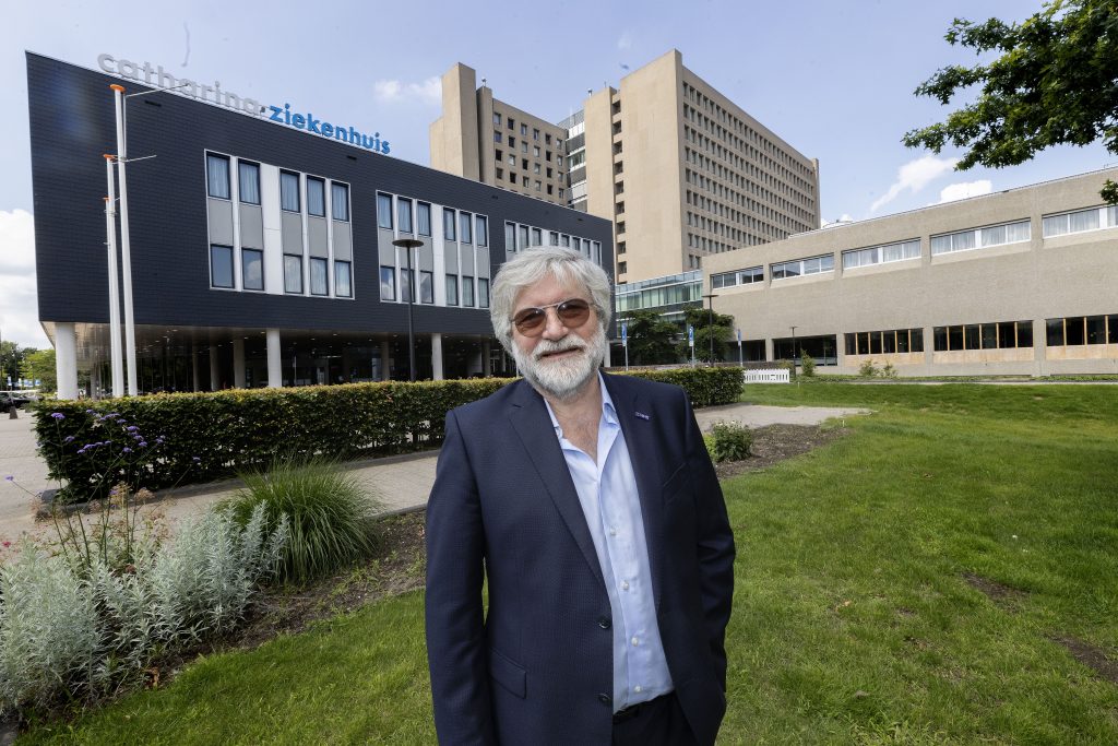 Professor dr. Harm Rutten in donker pak en zonnebril op gras voor het Catharina Ziekenhuis na ontvangst van de Gouden Legpenning.