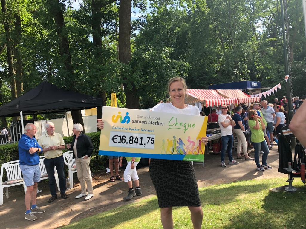 Vrouw met cheque van €16.841,75 voor Catharina Kanker Instituut op Samen Sterker evenement in Son en Breugel buiten.