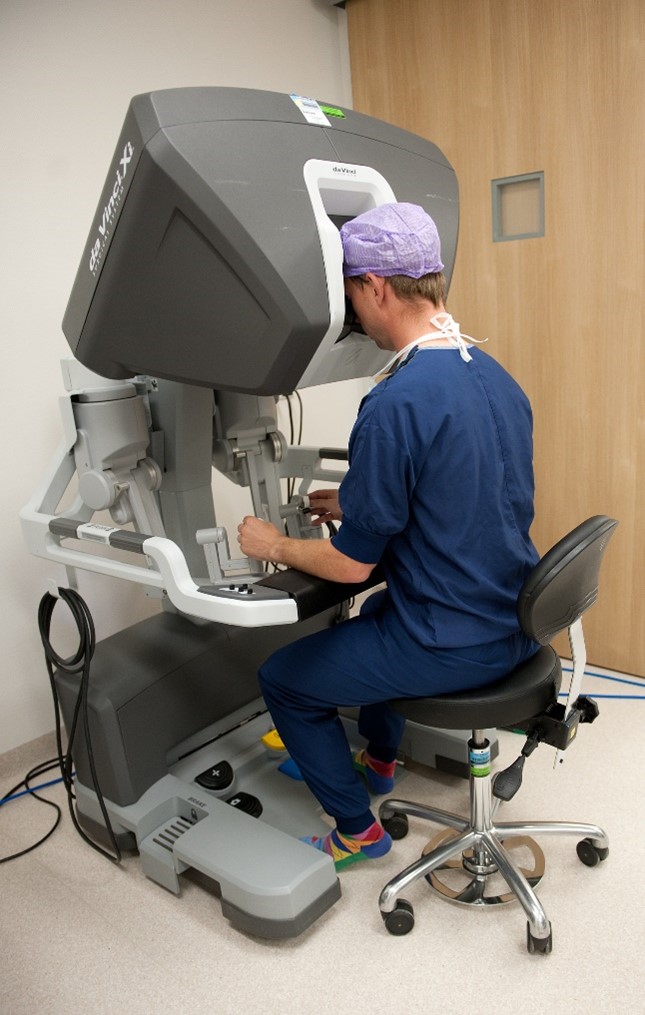 Persoon in OK-kleding bedient een robotconsole voor een Robot Geassisteerde Radicale Prostatectomie (RARP).