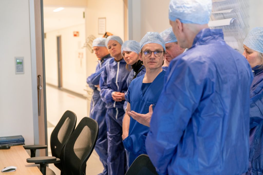 Een groep mensen in blauwe OK-kleding luistert in het Catharina Ziekenhuis naar Ernst Kuipers tijdens zijn werkbezoek.