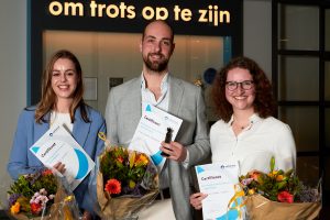 Drie mensen met certificaten en bloemen bij Catharina Wetenschapsavond 2023; Tessa Geraedts staat ertussen.