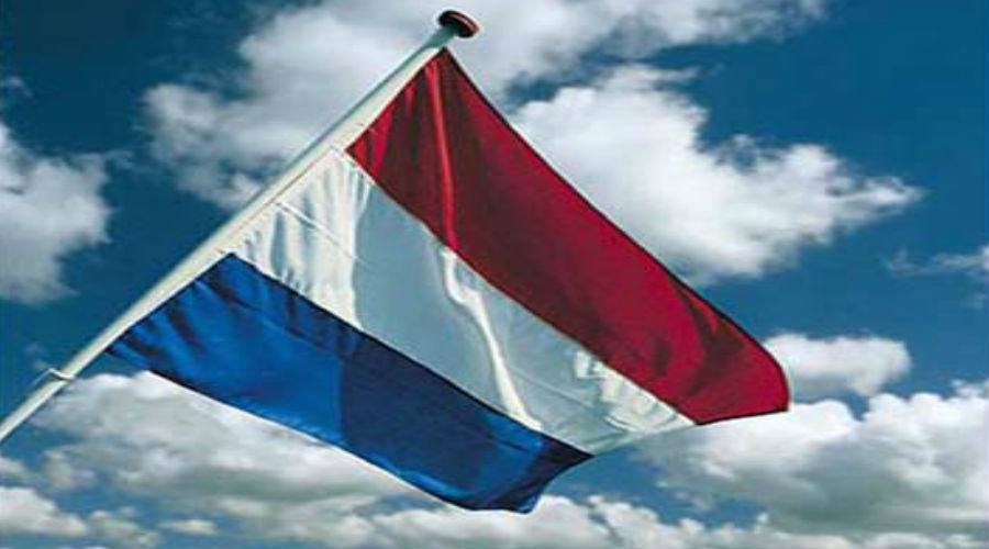 Een vlag met rood-wit-blauwe horizontale strepen wappert aan een mast onder een deels bewolkte lucht op Bevrijdingsdag.