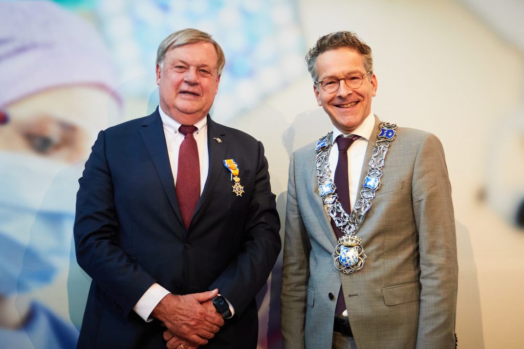 Twee mannen in pak. Links Hein Brackel met medaille, rechts een man met ambtsketen en bril.