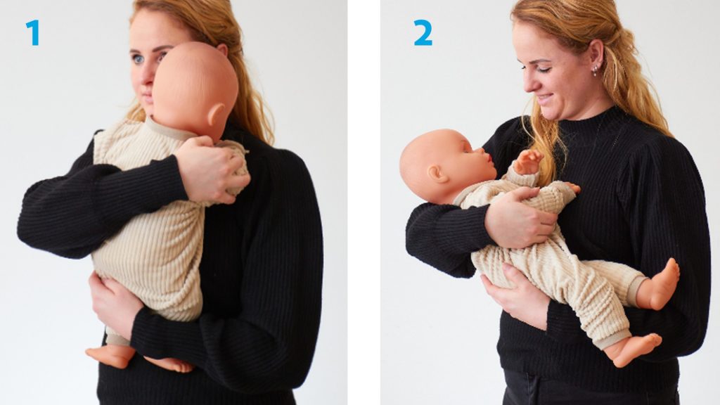 Vrouw in zwarte trui toont twee houdingen met babypop volgens OPBL: links rechtop, rechts liggend in armen.