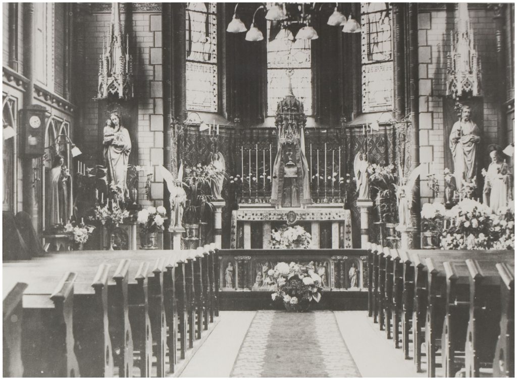 Zwart-witfoto van kerkinterieur met houten banken, bloemstukken en beelden bij een altaar; jubileum Catharina Ziekenhuis 50 jaar.