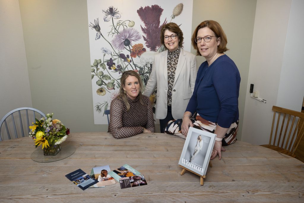Drie vrouwen aan een houten tafel met bloemen en boeken in kantoor van vrouwenzorgcentrum LEIN, Catharina Ziekenhuis.